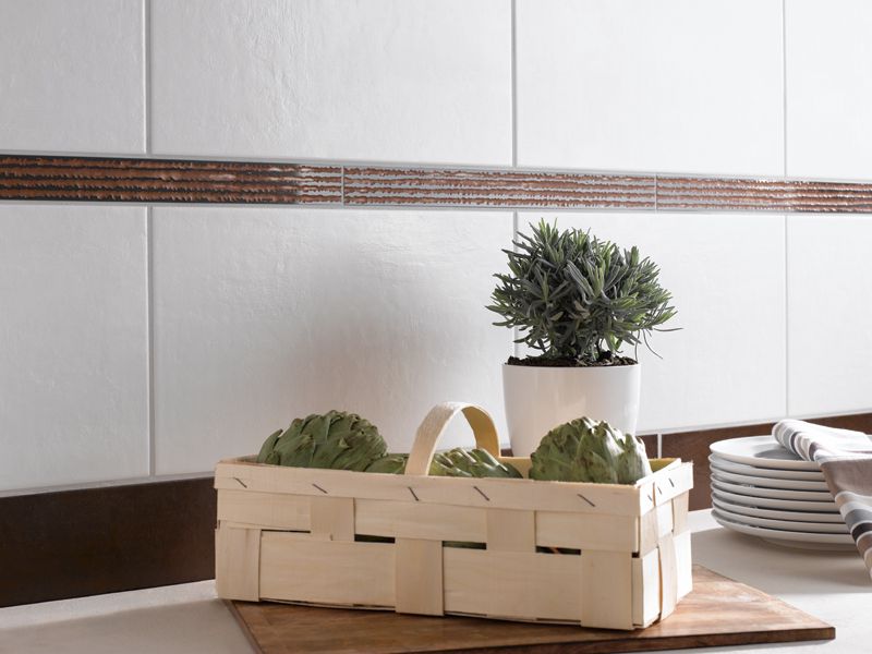 Ein geflochtener Korb mit Artischocken, daneben ein Lavendel-Topf und gestapelte Teller auf einer Küchenarbeitsplatte.